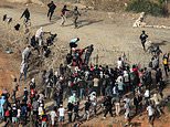 Migrants storm EU border: Hundreds swarm barbed wire fence after throwing rocks at Moroccan guards following social media call to force their way into Spanish enclave